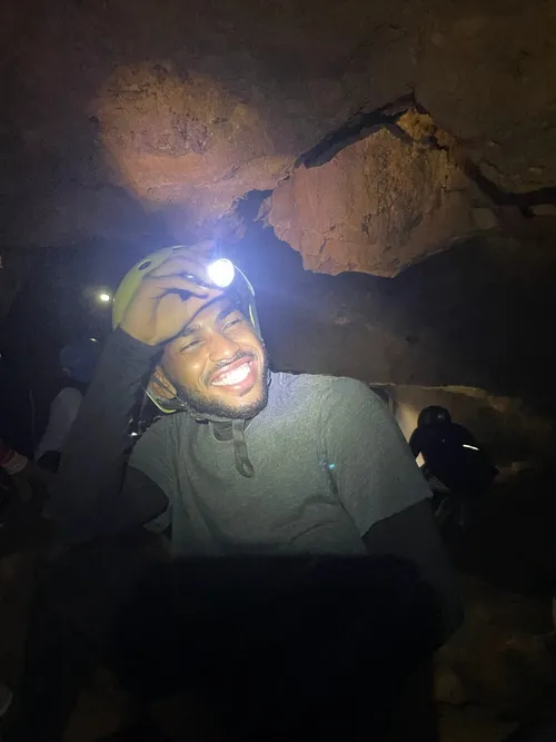 Amin Shennan smiling under a helmet lamp inside Gua Tempurung