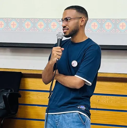 Amin Shennan speaking with a microphone at the SCS welcoming night